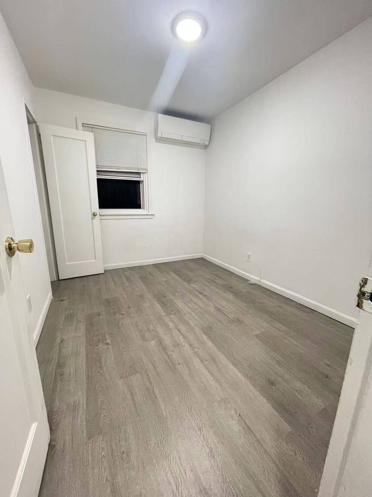 Guest bedroom with wide-plank wood-look flooring and mini-split AC in a Queens District 26 house for rent.