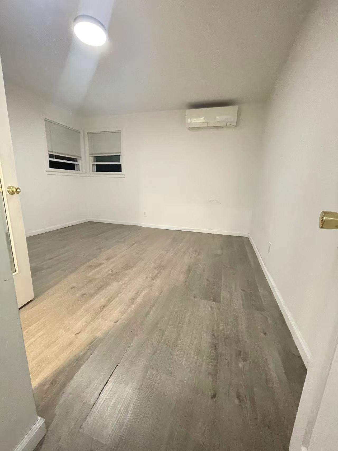 Bright primary bedroom with wide-plank flooring and ductless mini-split AC in a Fresh Meadows 11365 rental house.